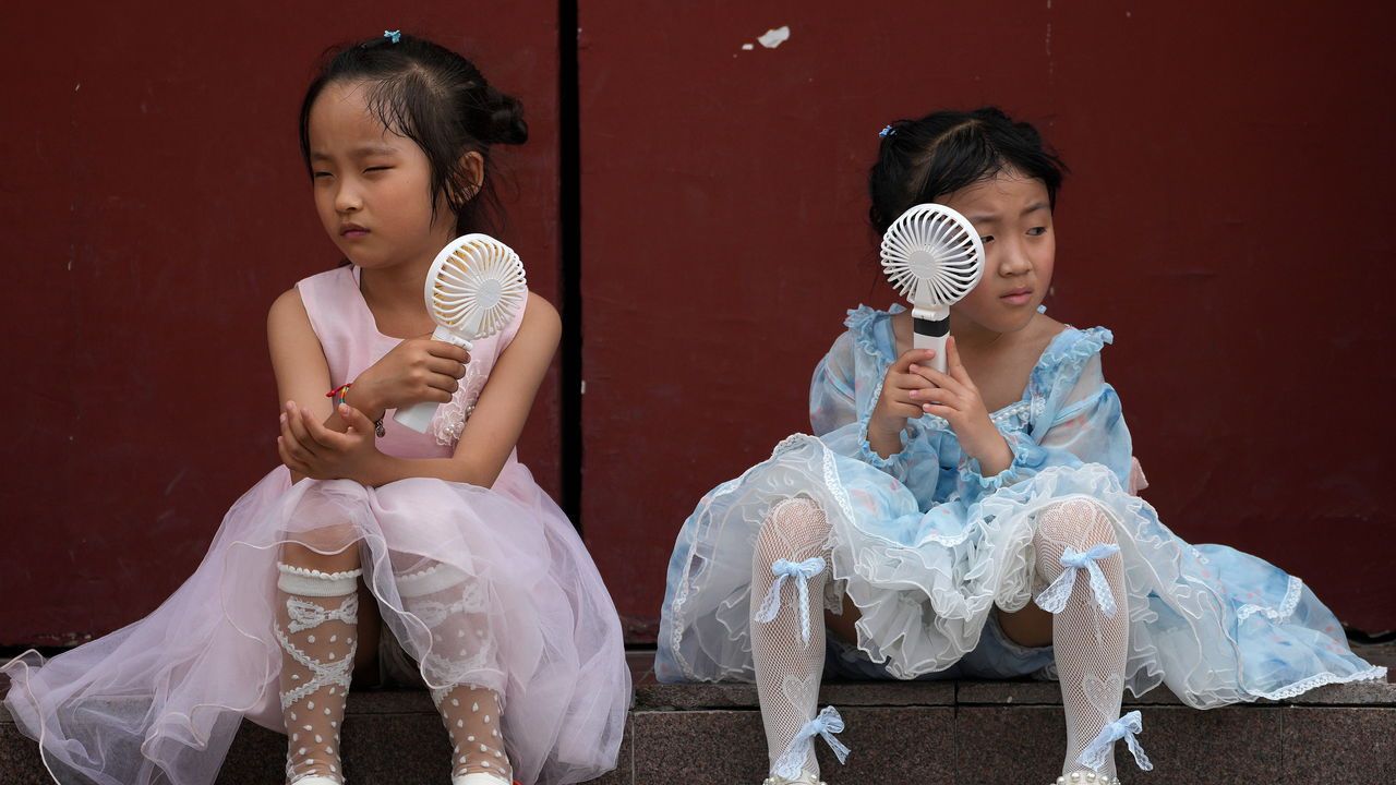 Children cool themselves with electric fans on a hot day in Beijing.