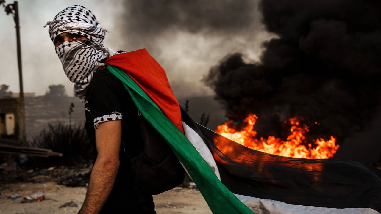 A Palestinian wears a Palestinian flag while protesting Israeli occupation in the West Bank.