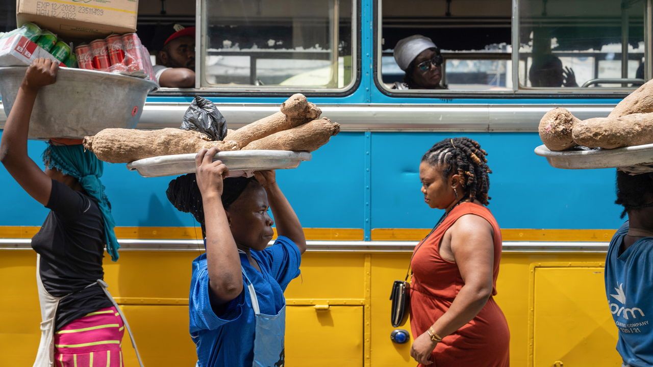 Street vendors pass a stationary bus in Ghana.