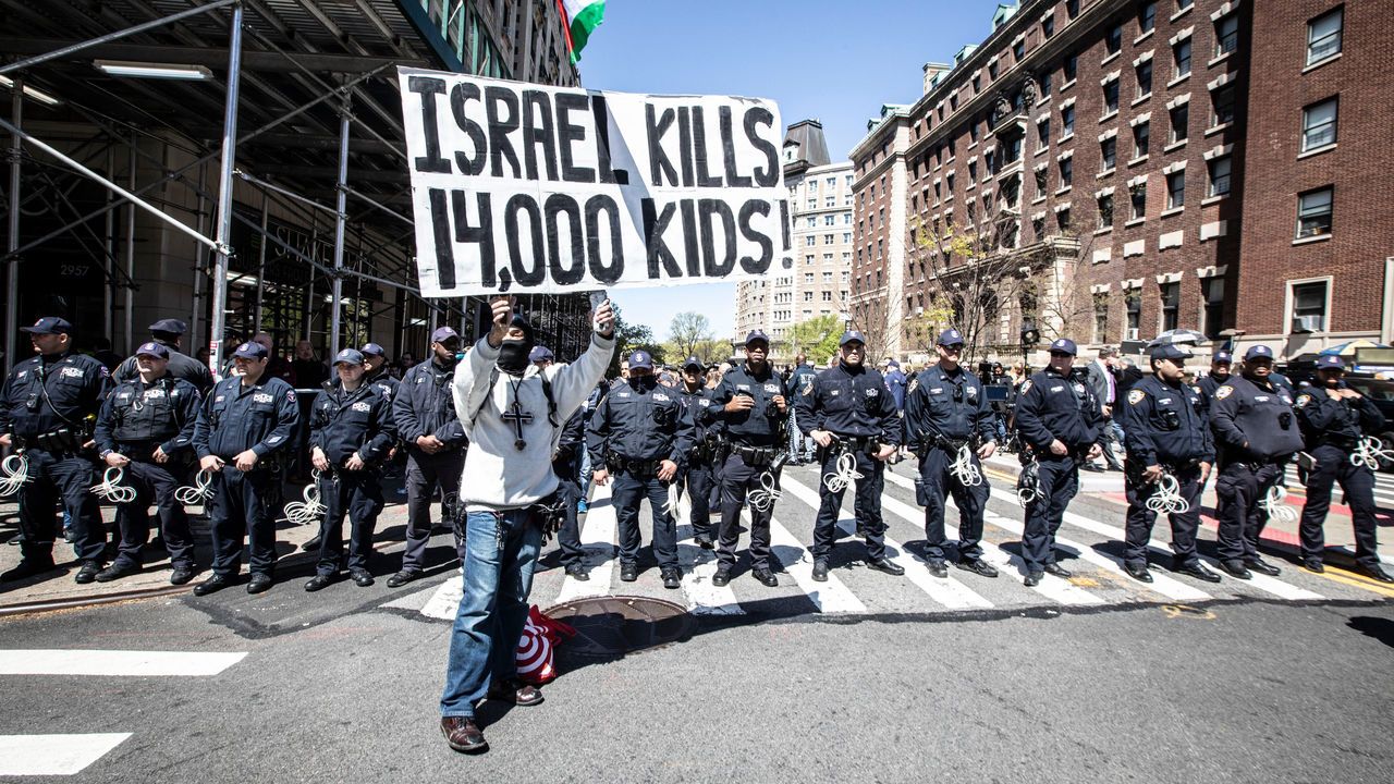 A protestor stands in front of dozens of New York City police officers across the street from Columbia University in Manhattan