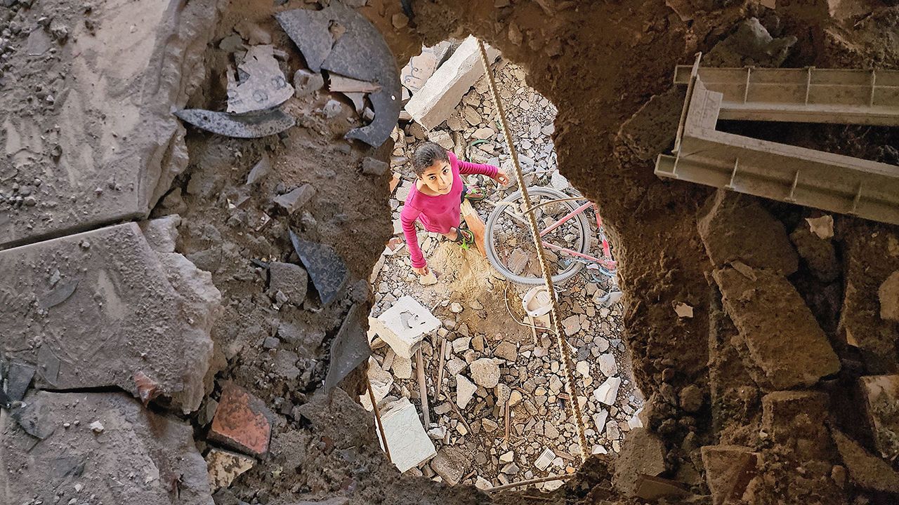 Palestinians, including children, collect remaining belongings from the rubble of destroyed houses in Rafah after Israeli attacks 