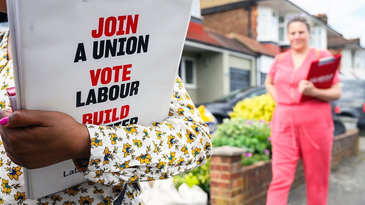 A Labour Party member holds a branded clipboard.