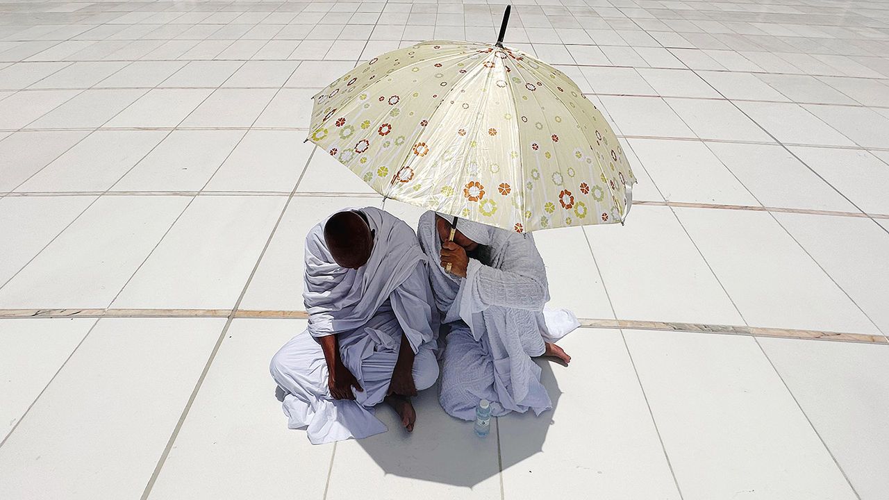 Muslim pilgrims take shade from the sun underneath an umbrella during the Hajj pilgrimage in Mecca, Saudi Arabia