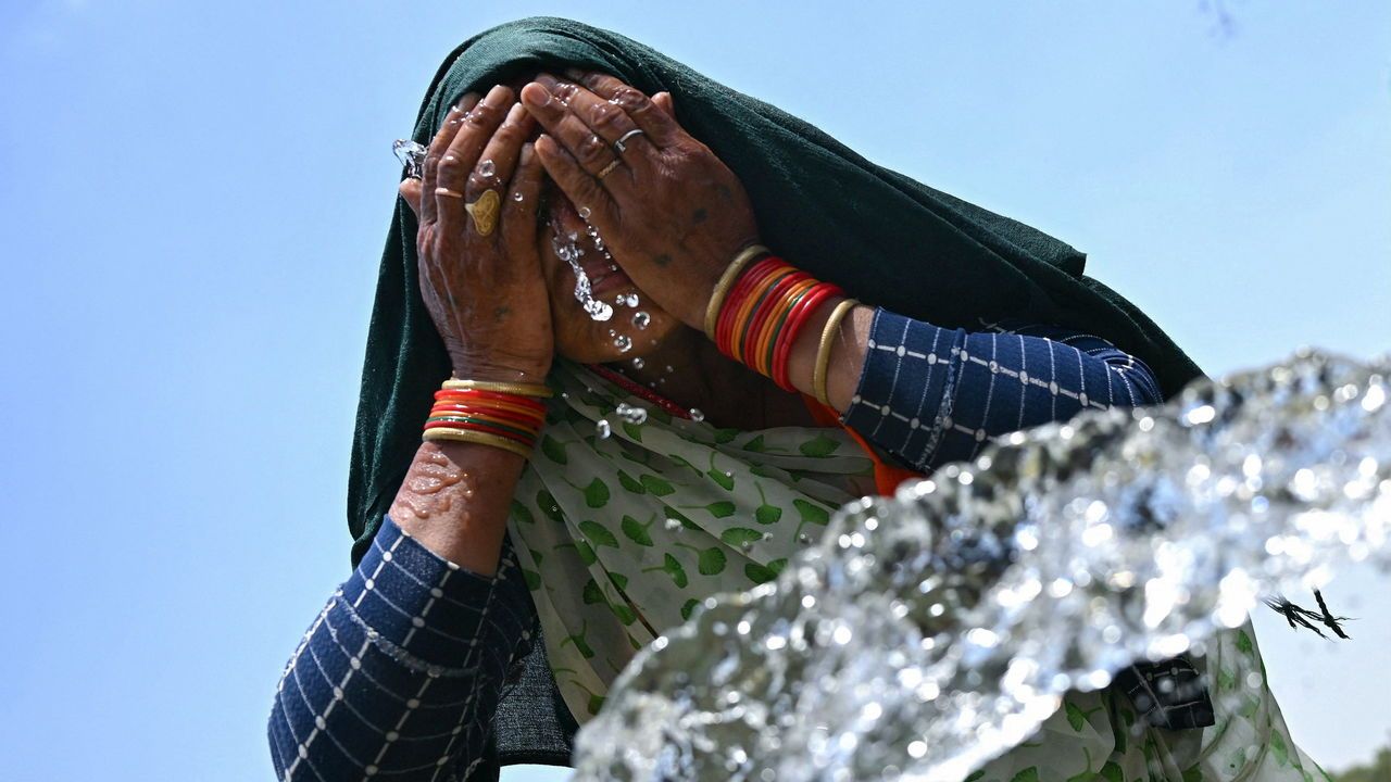 A woman splashes her face with water to cool off during a hot summer day in New Delhi, India on June 17th 2024