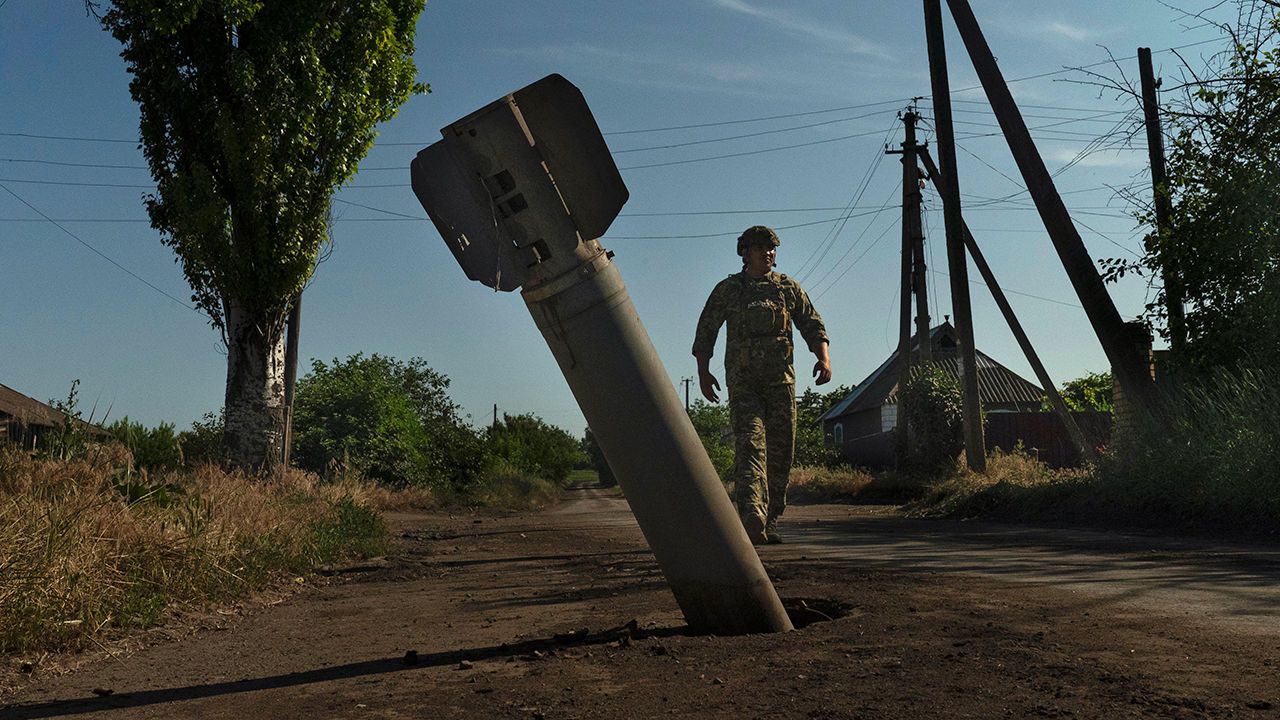 UKRAINE. Katerynivka, Donetsk. A soldier examines an unexploded rocket on the roadside.