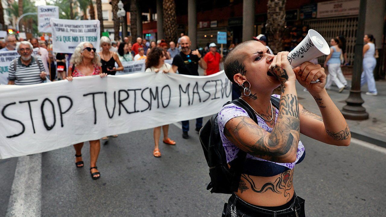 A demonstrator uses a megaphone as people protest against mass tourism.